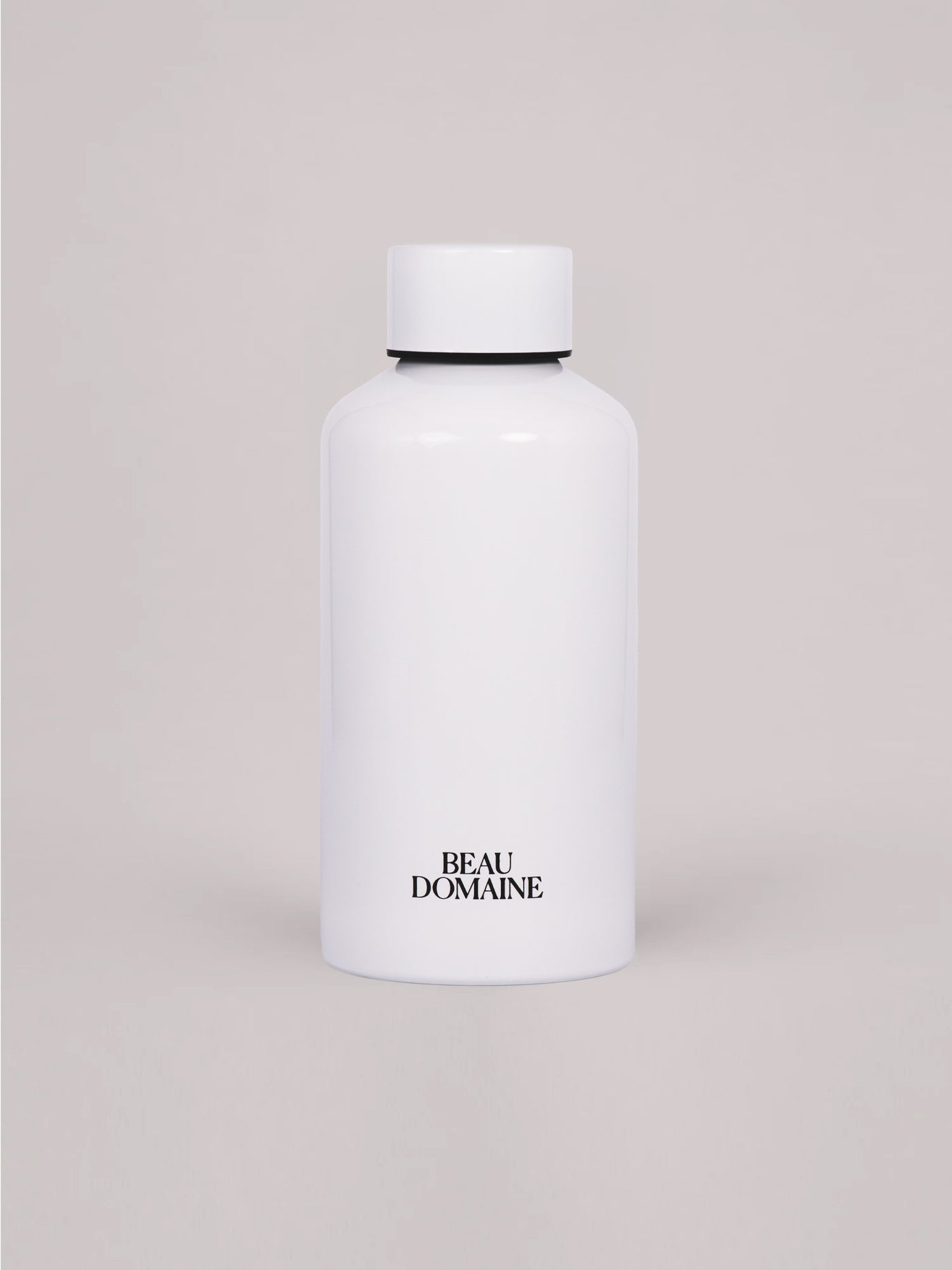 Flacon blanc avec la marque « Beau Domaine » sur fond beige